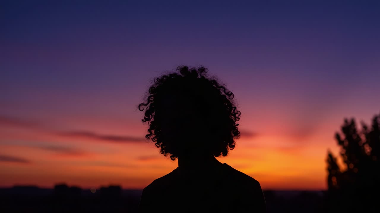 Captivating Sunset Silhouette: A Person with Curly Hair Against a Vibrant Evening Sky, Showcasing the Beauty of Nature and the Tranquility of Dusk