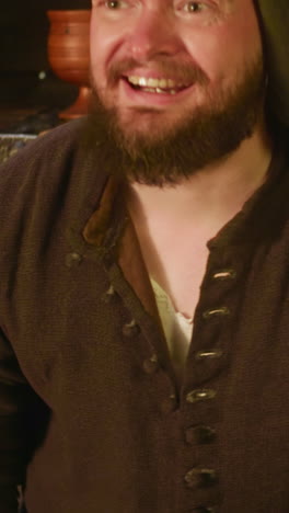 el vendedor barbudo busca un bolso con dinero en la tienda. el comerciante complaciente paga el impuesto de las ganancias al coleccionista en una taberna medieval. el hombre sonriente comercia en la tienda