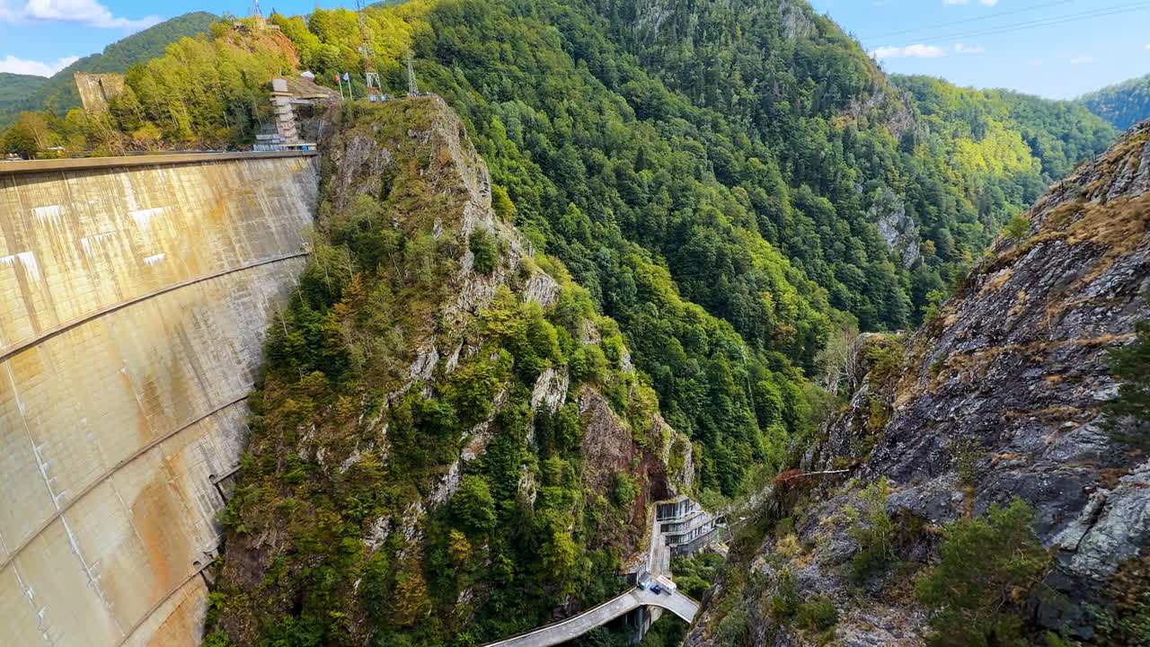 Vidraru Dam wall and surrounding mountains in Romania. Massive Vidraru Dam wall with forested mountains in the background, Romania