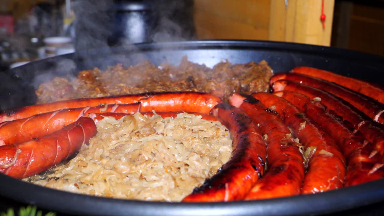 enlaces enteros de salchichas fritas, repollo salteado y cebollas en una sartén grande. cocina al aire libre