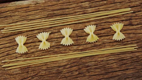 Bow-tie-pasta-and-spaghetti-on-wooden-table-background