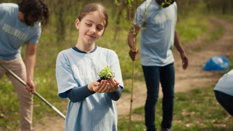 little girl holding a small green sprout with natural soil