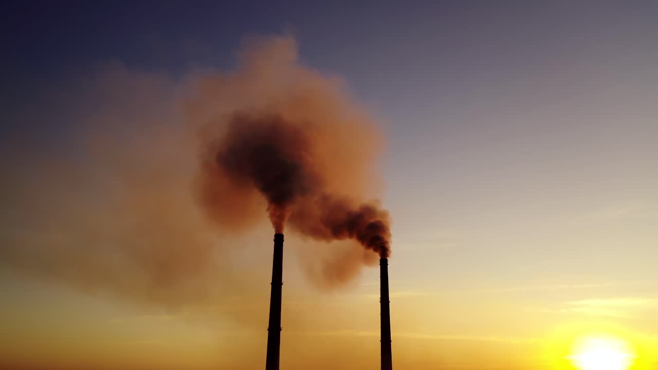 Orange smoke from pipes at sunset. Dirty emissions in the air on the evening sky background. Ecology pollution.
