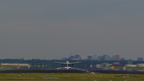 airplane landing on runway with city skyline in background