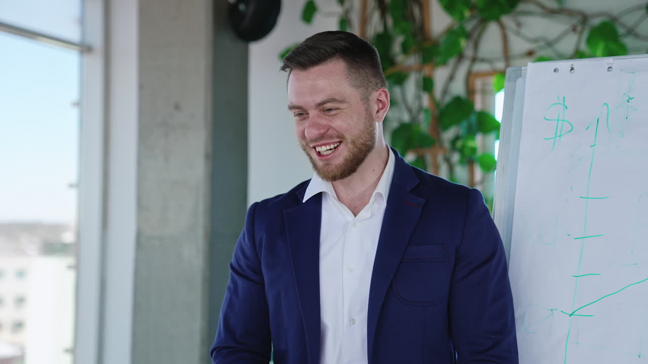 Smiling man in a suit standing at the flipchart and explaining something. Business presentation of reports in diagrams and charts. Working in an office environment.