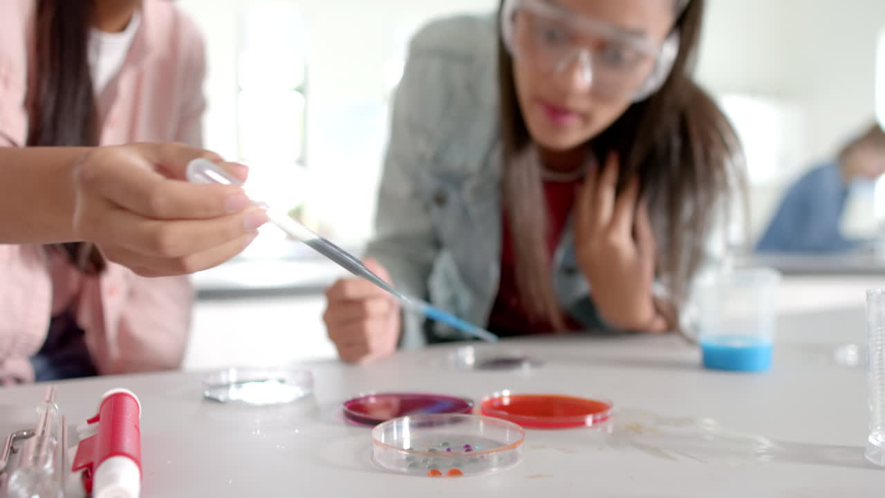 In high school, teenagers conducting science experiment with petri dishes and pipette