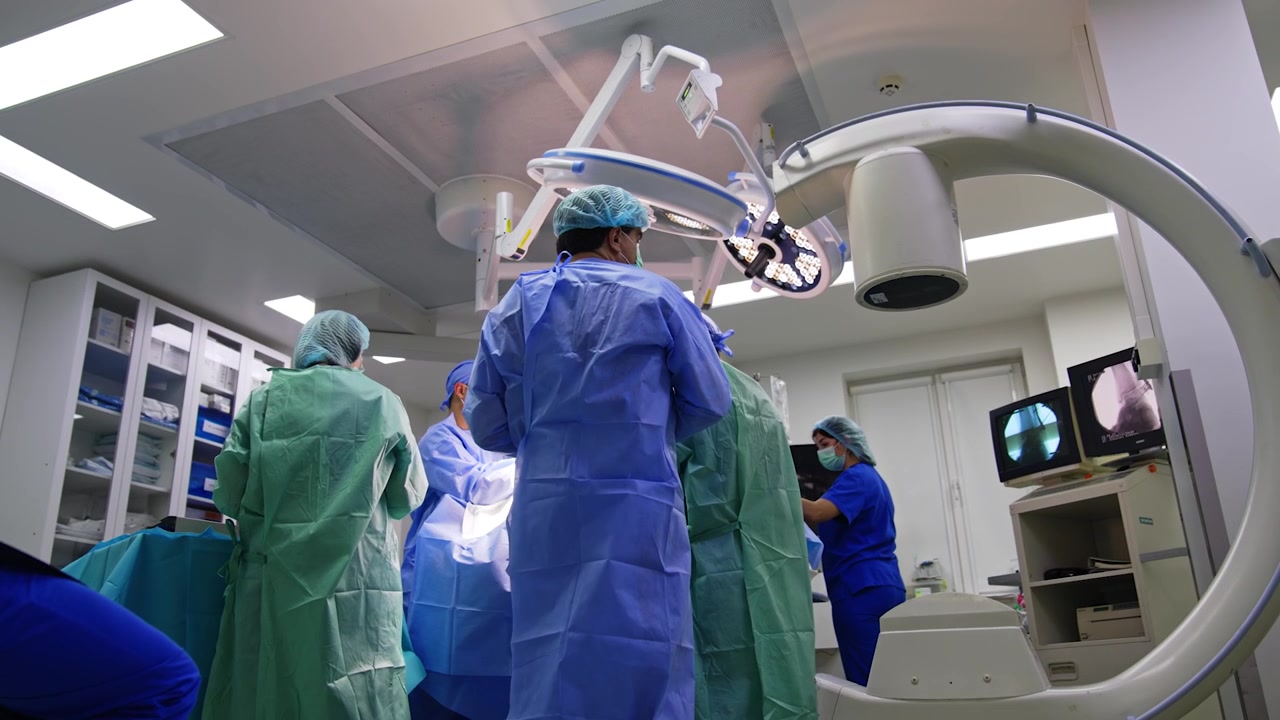 C-Arm machine standing nearby the medical team performing surgery. Team of doctors carry out the trauma operation. Low angle view.