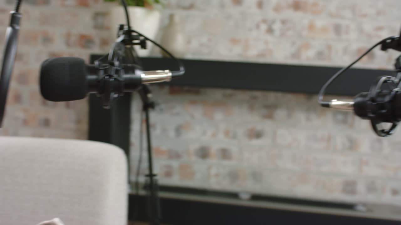 Afrikansk vært og kvindelig medvært taler i sofaen til en podcast med bommikrofoner