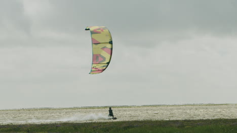 Epic-cinematic-slow-motion-shot-of-a-kite-surfing-surfing-at-the-local-beach-of-Sankt-Peter-Ording,-Germany