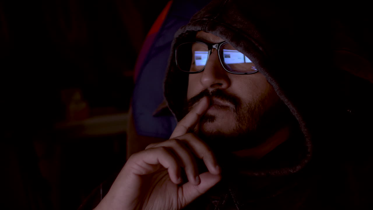 hombre pensando profundamente mientras trabaja en la computadora con gafas y sudadera con capucha