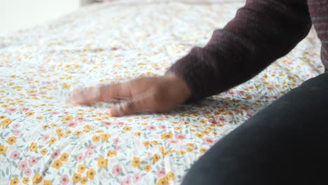 persona que hace una cama con ropa de cama floral