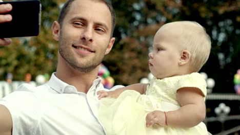 family with baby in park taking selfie by mobile phone