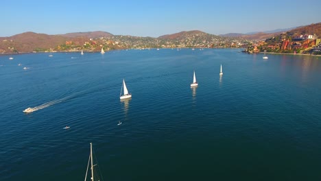 Herunterfliegen-über-Segelbooten,-Die-Um-Eine-Bucht-Mit-Ruhigem-Wasser-Vor-Der-Küste-Von-Zihuatanejo,-Mexiko,-Rasen