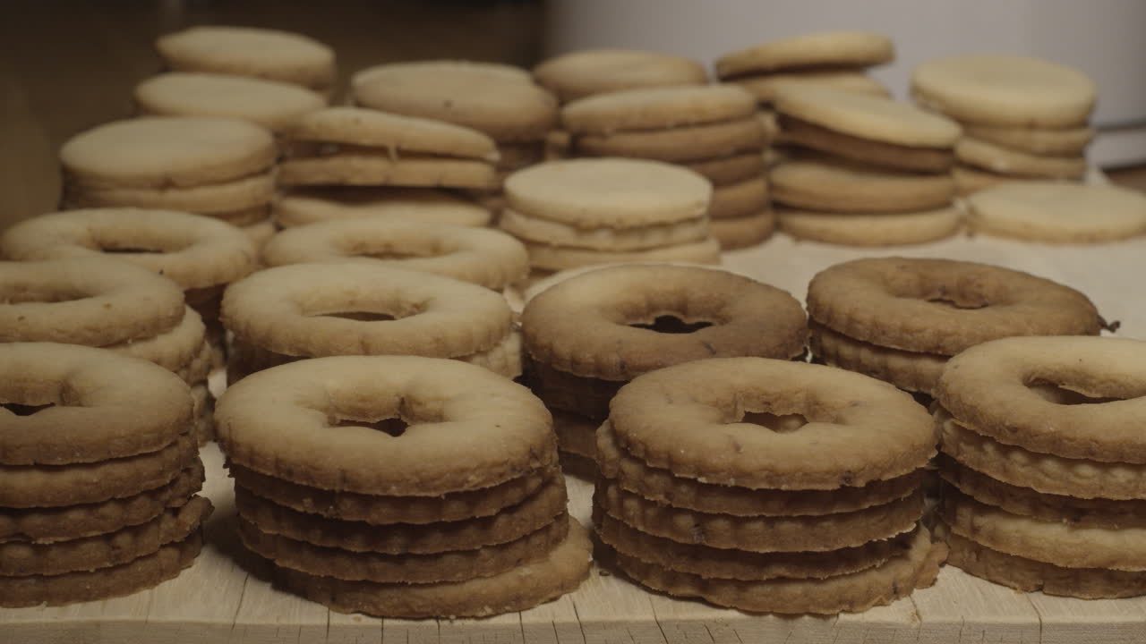 Stacks of linzer cookies lined up ready for jam, slow pan