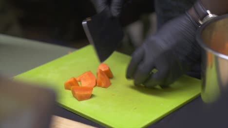 Raw-orange-carrots-cut-using-butchers-cleaver-on-green-chopping-board