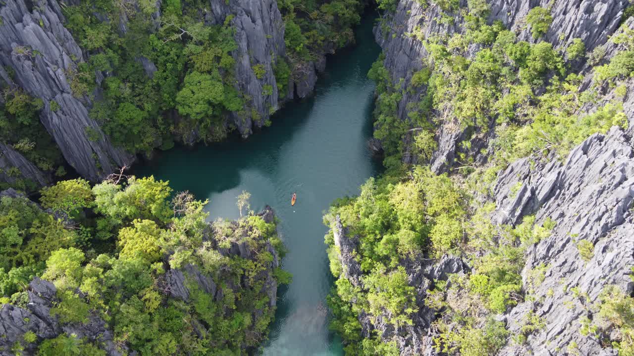 Un kayaker solitario in kayak sulla piccola Laguna di El Nido tra affioramenti carsici verticali lussureggianti.