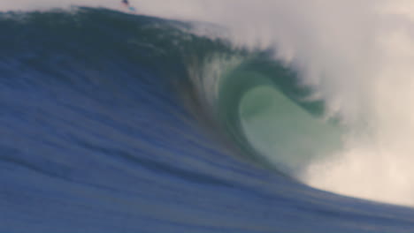 massive ocean wave rolling in slow motion at golden hour, with a surfer in the background riding the swell