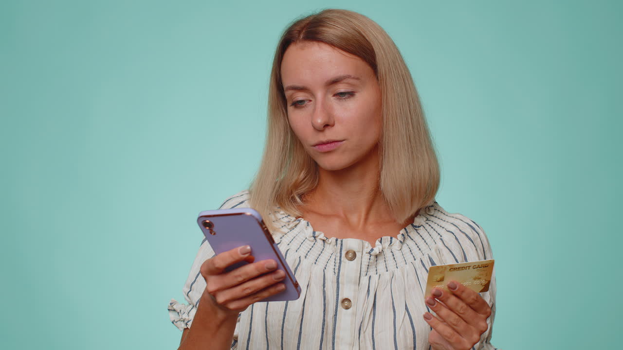 Молодая женщина использует кредитную банковскую карту и смартфон при переводе денег для покупок в Интернете