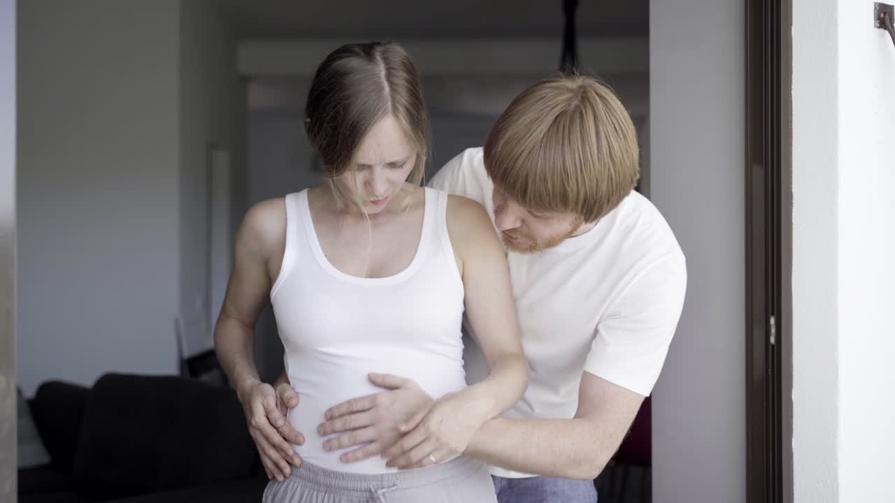 счастливый муж массажирует живот своей жены.