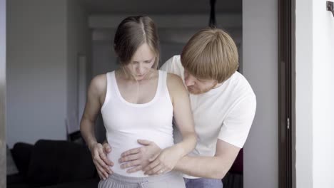 happy husband massaging belly of his wife