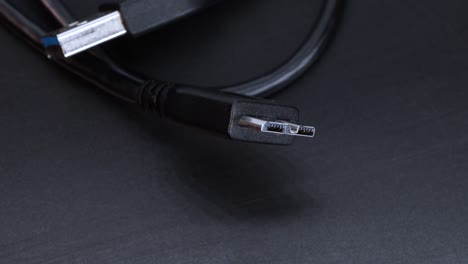 Vista-De-Cerca-Del-Conector-Del-Cable-Del-Disco-Duro-Ssd,-Movimiento-Giratorio-Sobre-Fondo-Negro-En-4k,-Toma-Macro