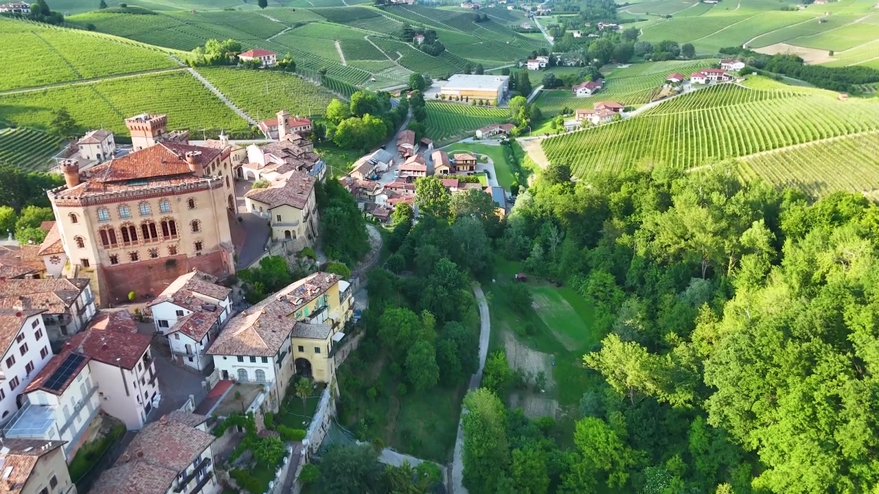 Una ripresa aerea con drone rivela l'architettura storica italiana circondata da lussureggianti colline ondulate di vigneti verdi.