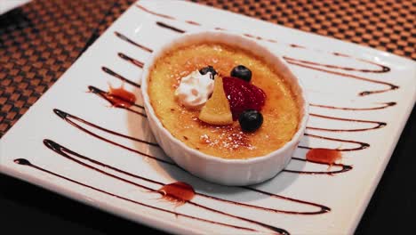 flambéed flan with berrys on a white plate on the table of a luxury restaurant