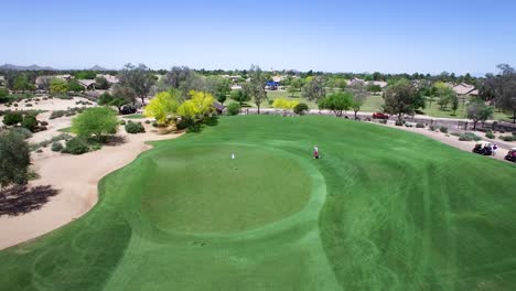 Aerial-lone-golfer-walks-on-to-the-perfectly-manicured-green,-Scottsdale,-Arizona-Concept:-golf-for-good,-charity