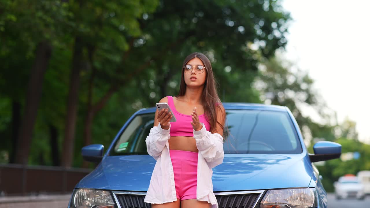 mujer en un traje rosa por un coche azul
