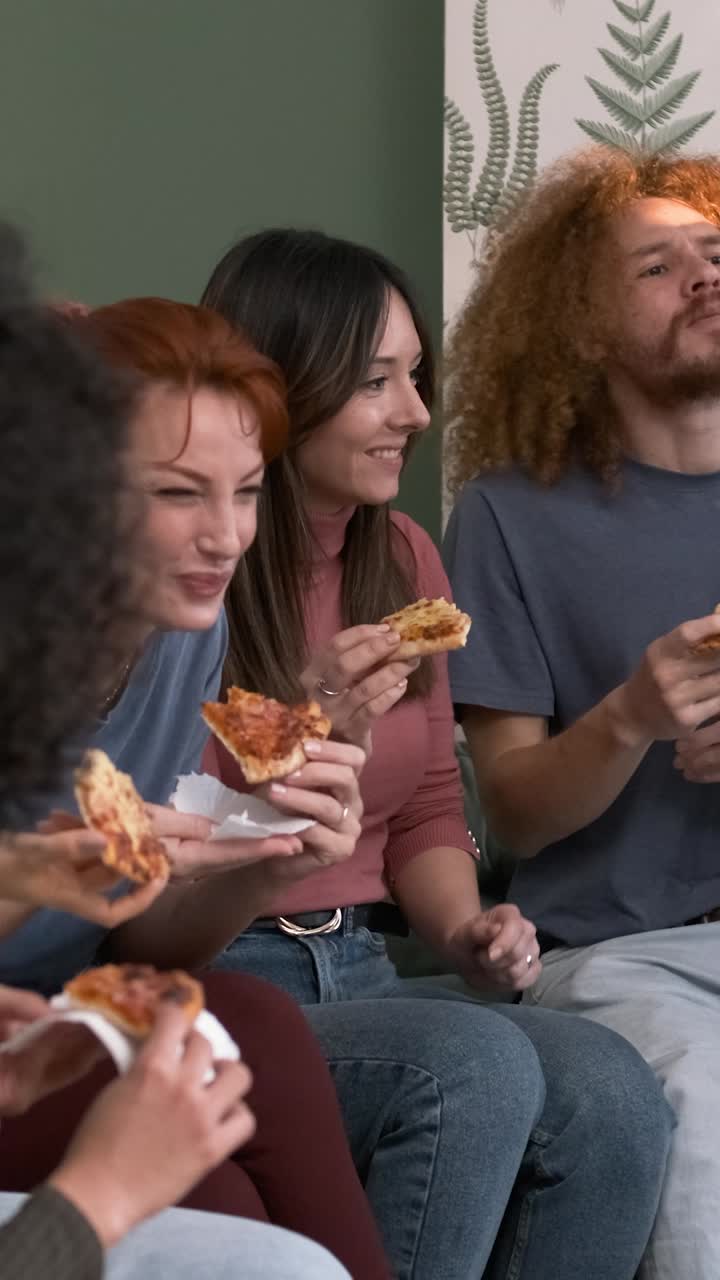 Diverse friends cheering up for woman bringing pizzas during weekend party at home