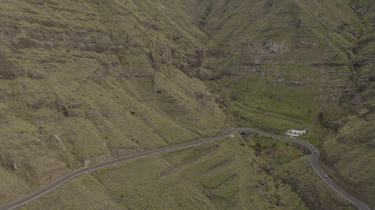 toma panorámica de un camión conduciendo a través de una carretera con curvas en un cañón con montañas