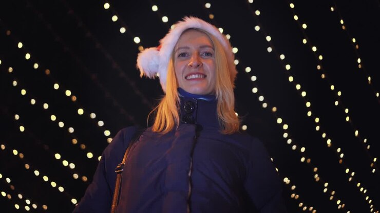 Una donna con un cappello da Babbo Natale si porta il dito al naso - un simbolo segreto