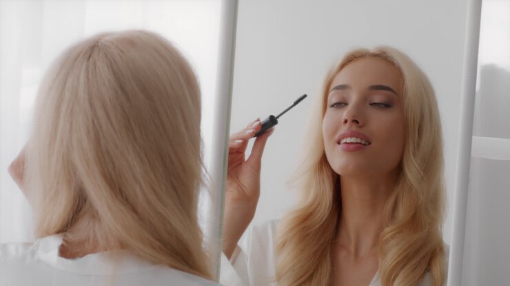 Donna che applica il mascara davanti a uno specchio