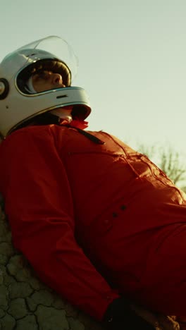 exhausted astronaut collapses on a rock with helmet on an empty planet