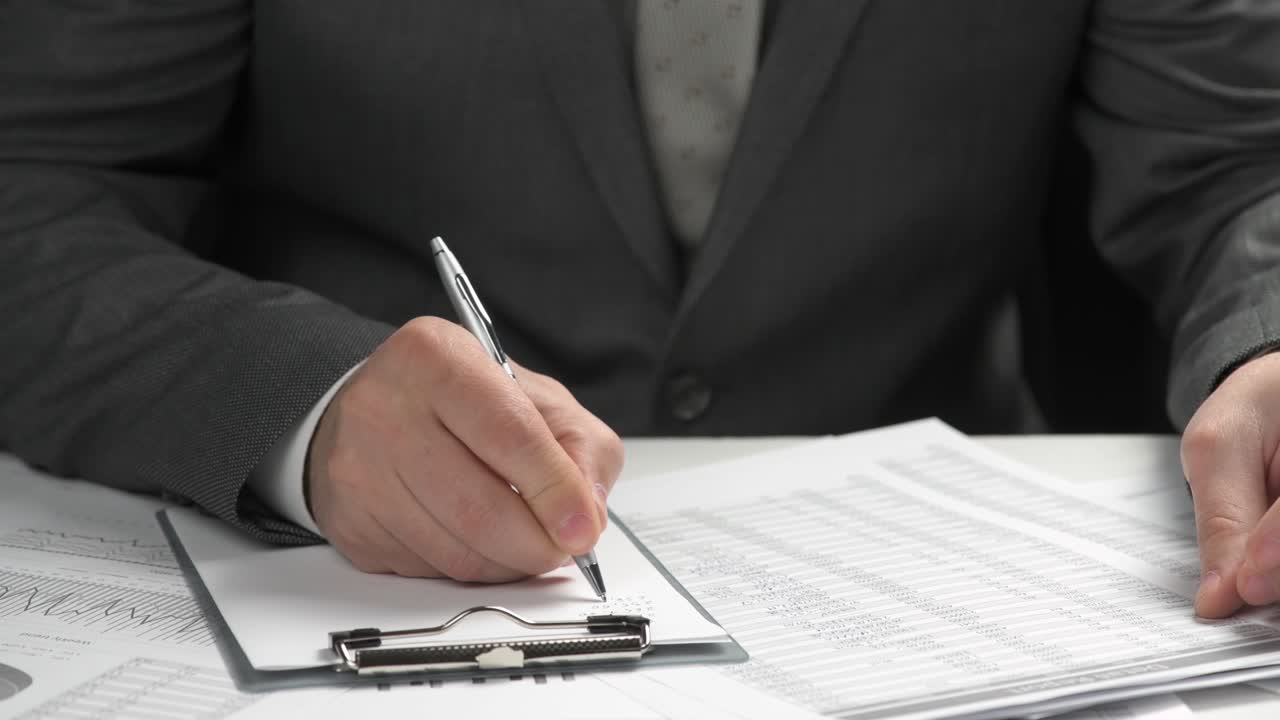 Businessman working and calculating finance. He reads and writes reports. Business financial accounting concept. Closeup hands.
