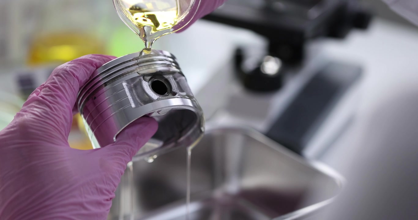 Uno scienziato versa liquido giallo in un cilindro sotto la luce del laboratorio.