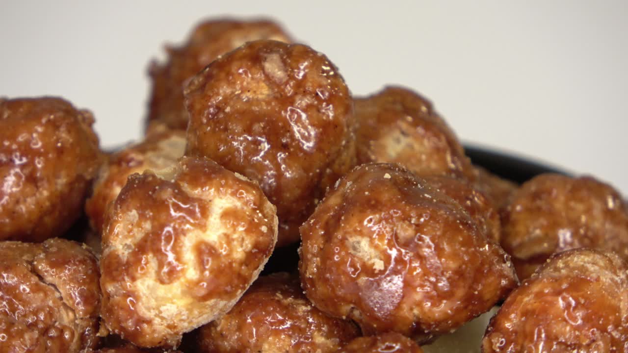 색 배경에 작은 그에서 회전하는 많은 캔디 매카다미아 견과류의 루프 가능한 영상입니다.