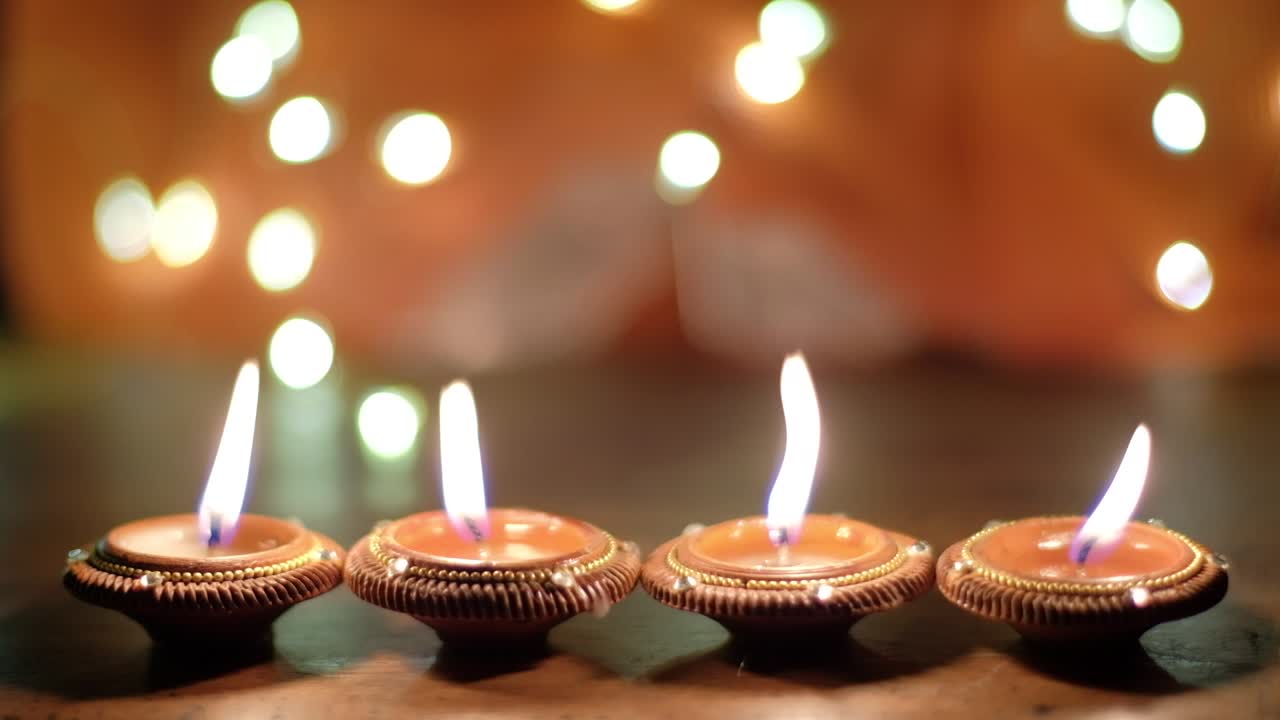 Static shot of light wax candles diya being blown to smoke and a human hand collects and readjust some with out-of-focus bokeh background during the celebration of Hindu festival of lights or Diwali