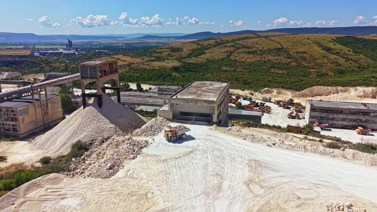 Cava in attività con macchinari e materiali in un cantiere durante una giornata di sole