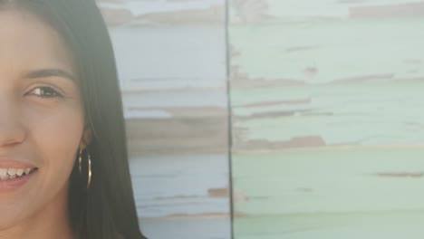 portrait of smiling hispanic woman in front of weathered wooden wall in sun, copy space, slow motion