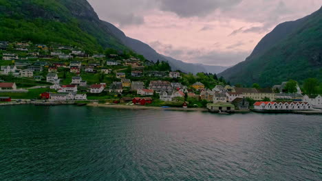 drone aéreo disparado volando sobre el agua del lago con la vista de las casas de la ciudad a lo largo de la ladera de la montaña a lo largo de la orilla en un día nublado