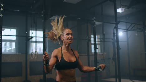 strong muscular young woman rope skipping as warm up. fitness concept. young slim woman jumping with skipping rope in gym. close-up of female feet jumping in mid air whilst using skipping rope.