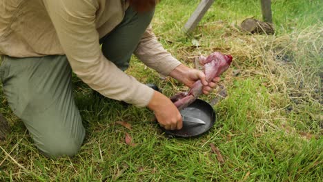 australian bushman cuts up a skinned rabbit that he hunted out in the bush