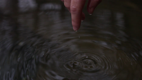 Female-hand-emerges-from-water-and-form-droplets-in-slow-motion