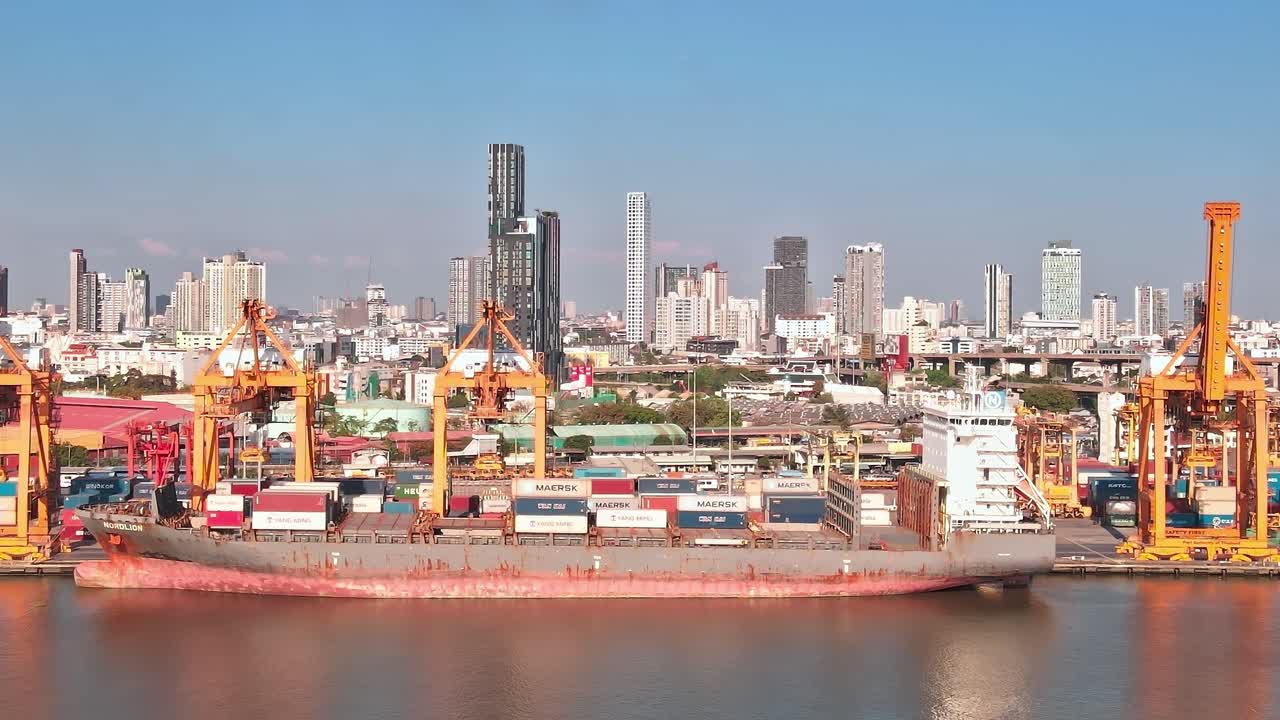 Cargo ship docks at Bangkok port with city skyline in background during day