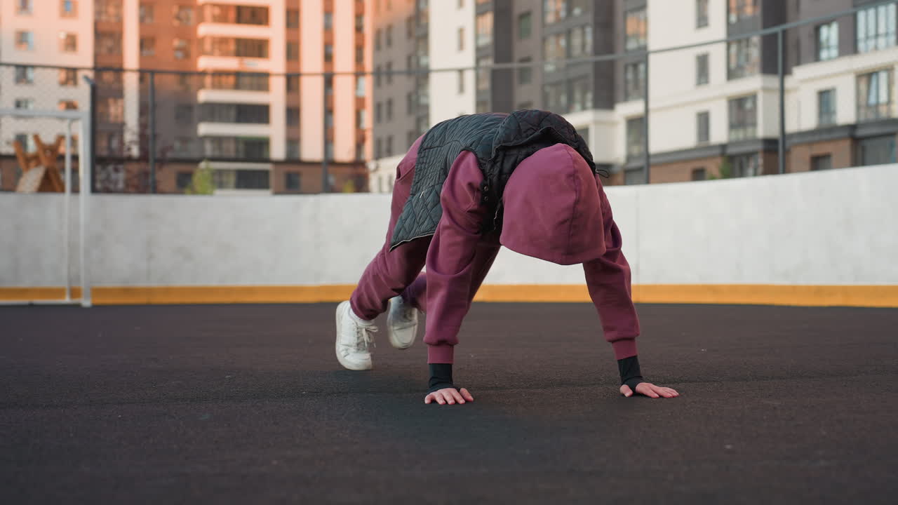 Determined trainer executing foot crawl exercise with hands on floor moving legs simultaneously on outdoor urban court showcasing core strength endurance coordination in dynamic fitness session