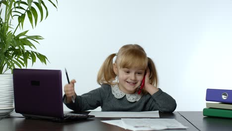 Funny-little-child-girl-boss-manager-emotionally-talking-on-mobile-phone,-sitting-at-computer-table