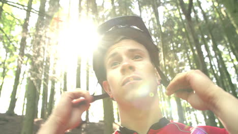 hombre con casco de seguridad de sujeción de bicicleta de montaña en el bosque