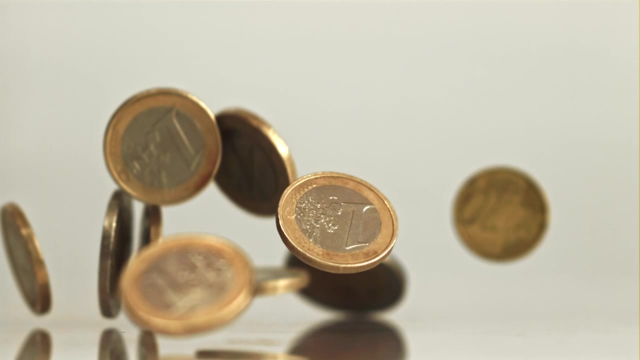 Monete di euro che cadono e atterrano su una superficie riflettente al rallentatore