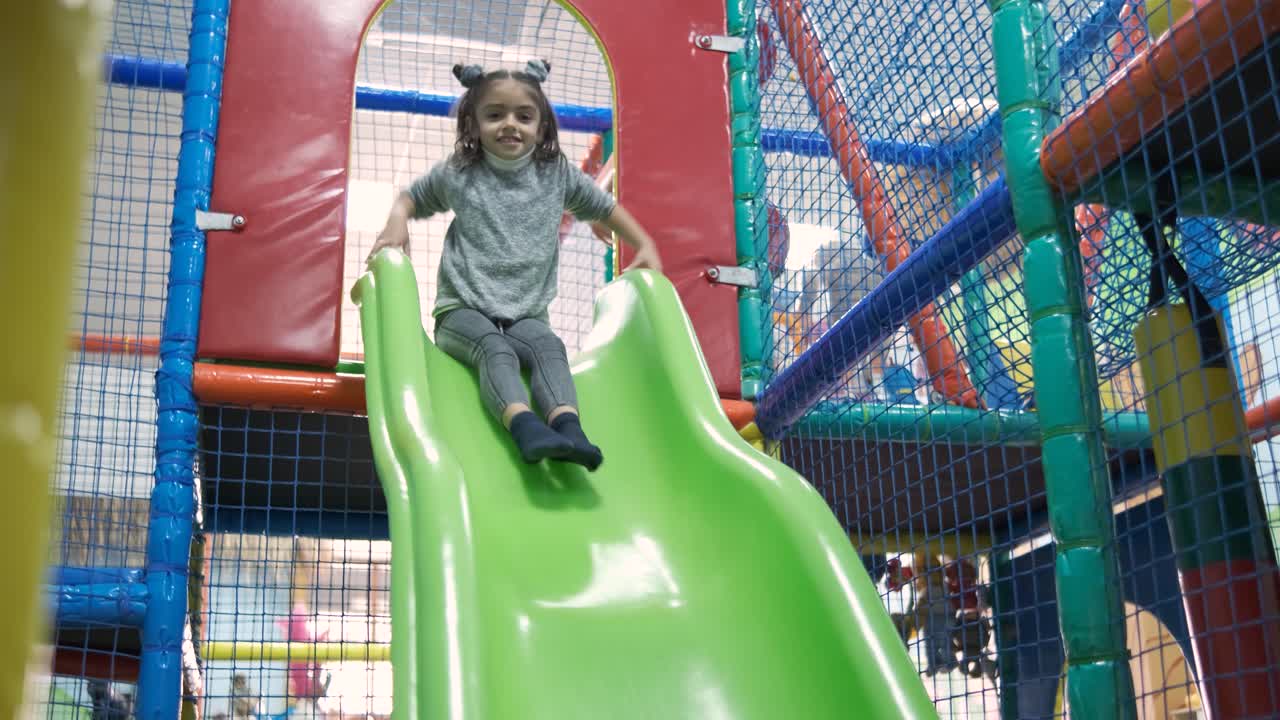 Little girl riding on slide in entertainment center